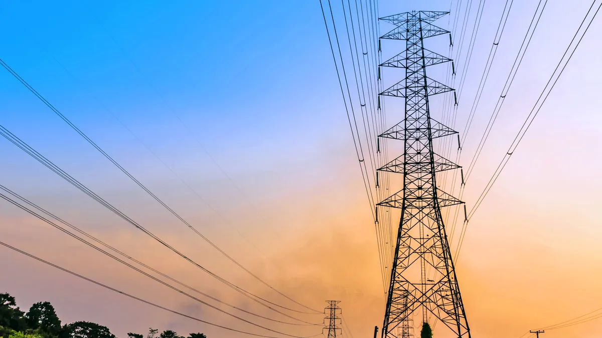 Electric transmission lines against a blue and yellow sky.