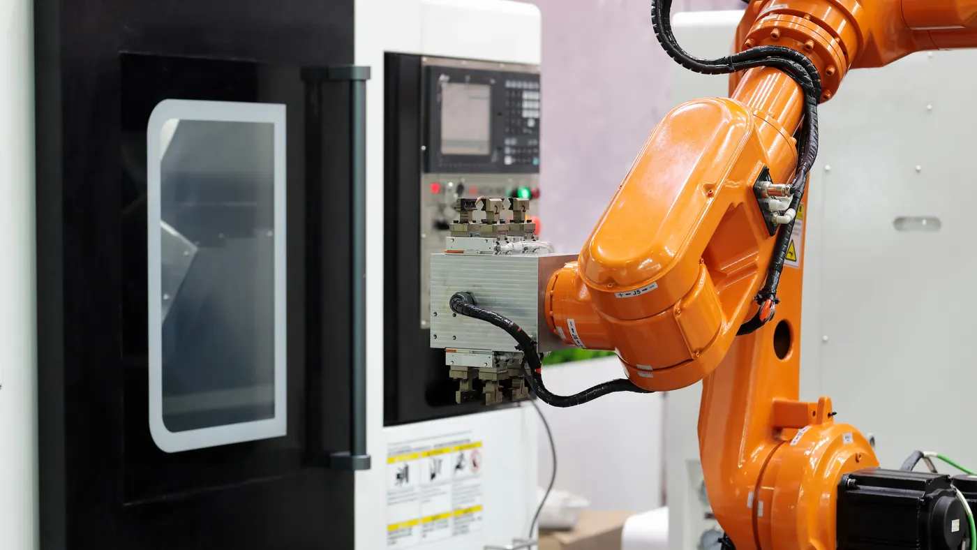 An orange robotic arm at a manufacturing facility