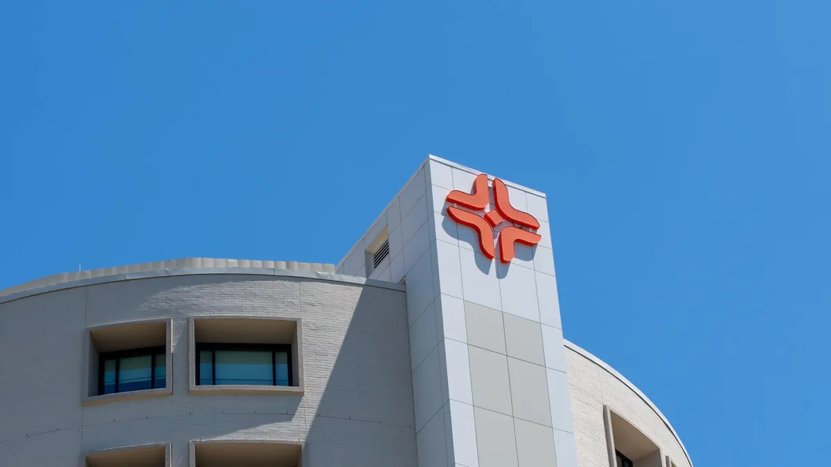 Logo of HCA Houston Healthcare on the top of a modern hospital building under a clear blue sky.