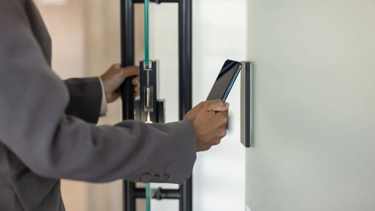 Business professional using smartphone for secure access to modern office building.