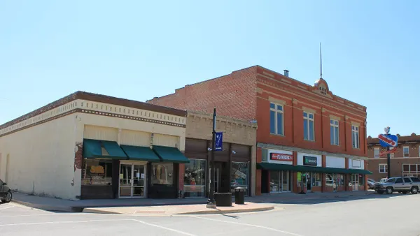A wide street with one and two-story retail buildings on a sunny day.