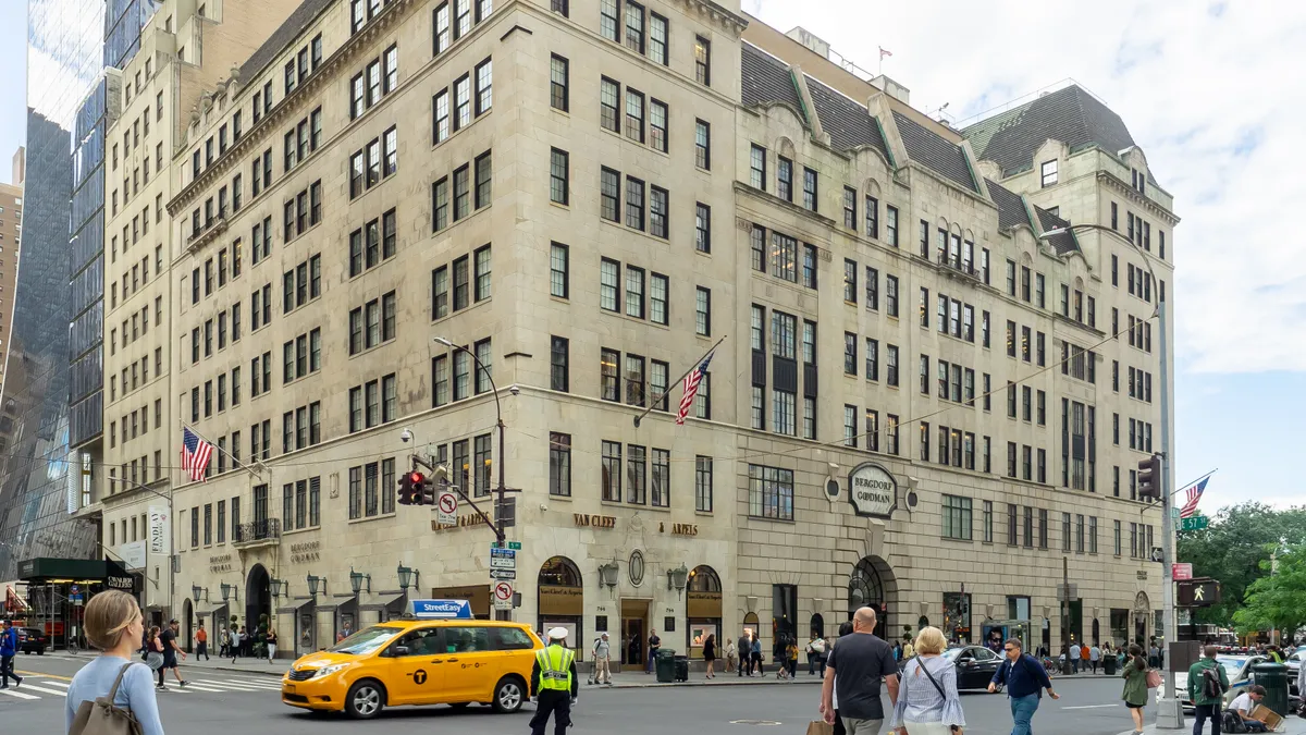 A yellow cab drives past a traffic cop as people walk near a big 19th century building.