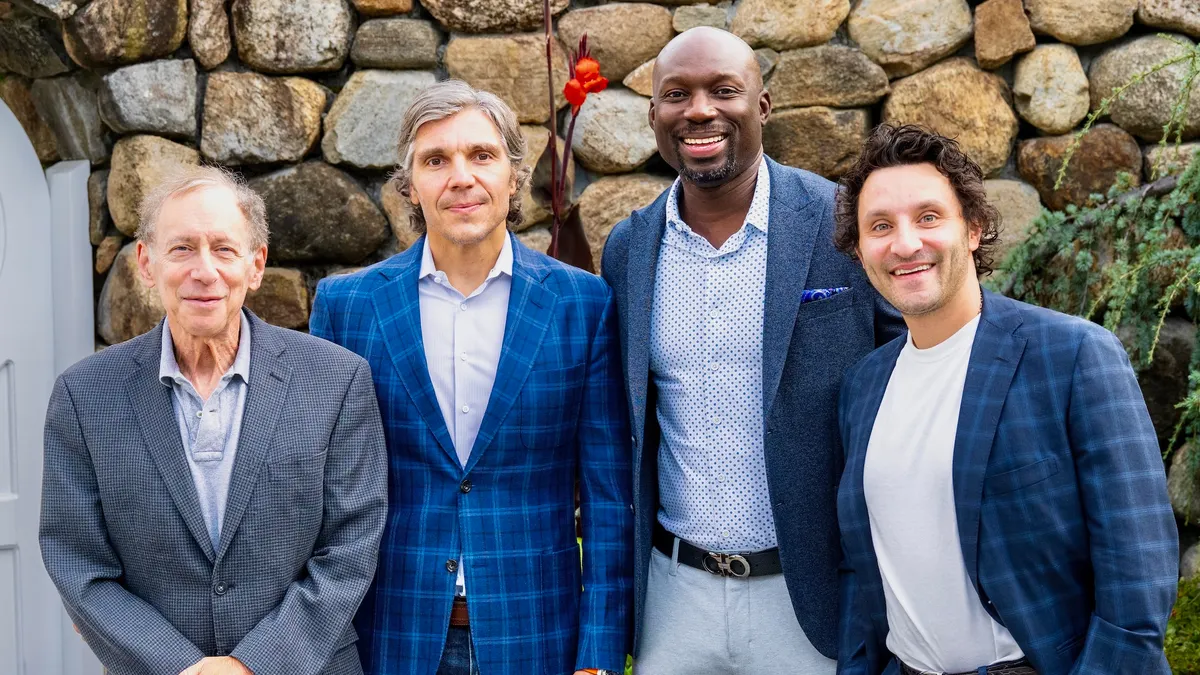 Bob Langer, Corey McMann, Kwesi Frimpong-Boateng and Michael Langer stand for a portrait in front of a wall of rocks.