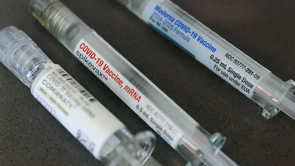 Boxes of COVID-19 vaccines from Pfizer and Moderna sit side by side.