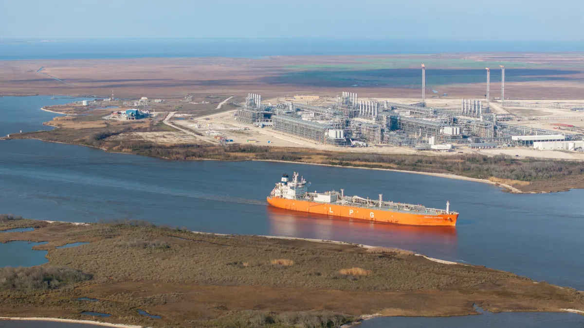A cargo ship passing by a liquefied natural gas plant.