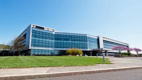 The Olympus U.S. headquarters building is shown against a clear blue sky.