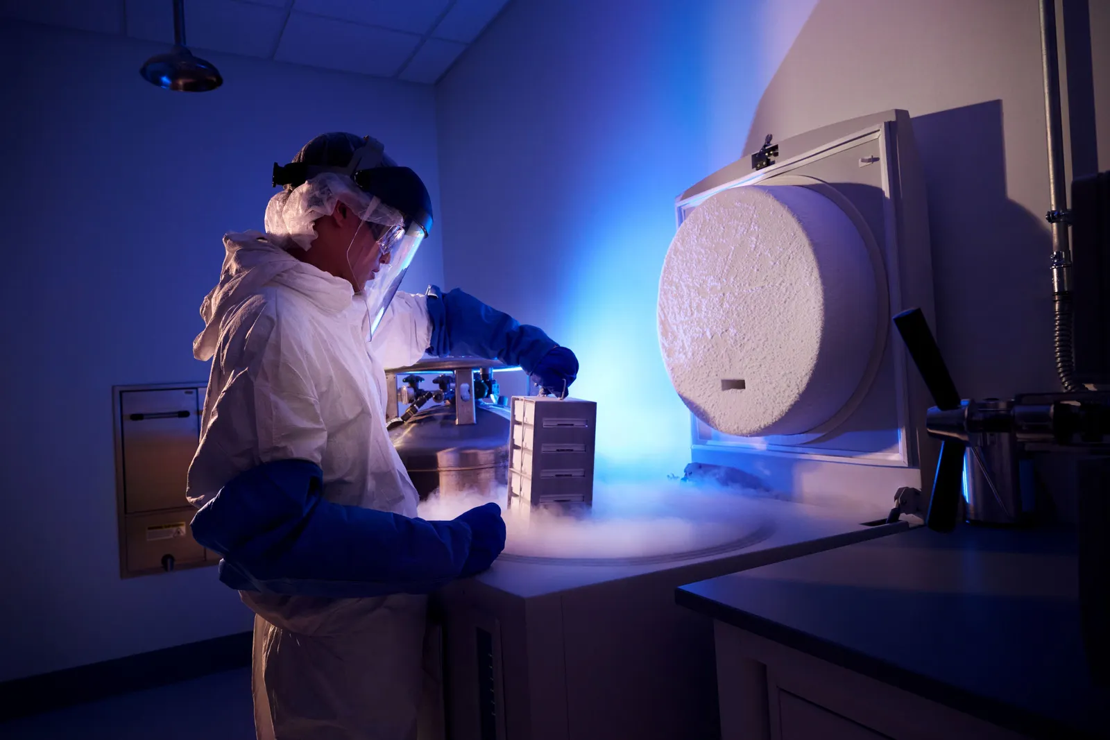 A worker pulls samples out of cryogenic storage.