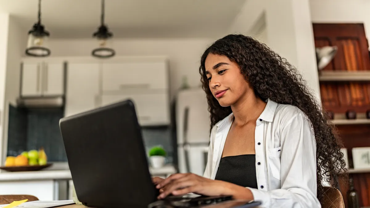 A young woman works on a laptop.