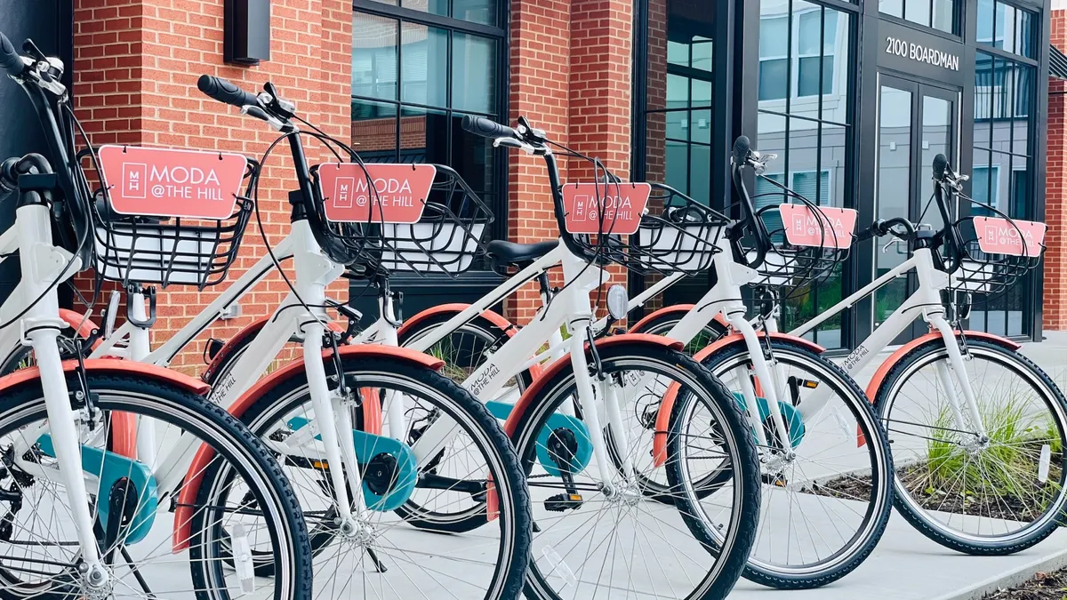 A row of bikes with baskets branded "Moda at the Hill."