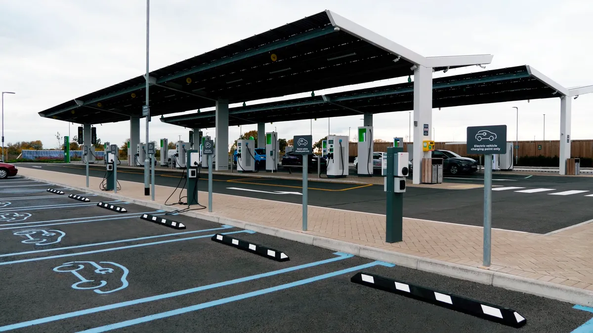 Empty parking stalls are equipped with electric vehicle chargers, under a canopy that contains solar panels.