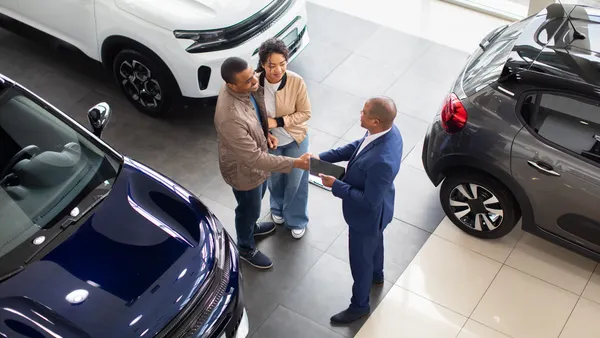 African American couple shaking hands with dealer in showroom, celebrating agreement on new car purchase, lifestyle and transport concept of business and success