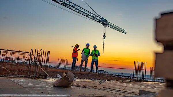 Three construction workers look at plans on a jobsite.