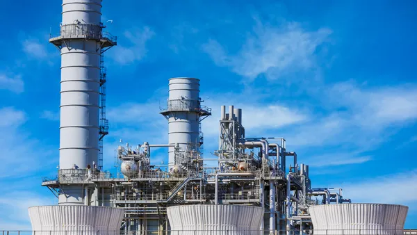 A natural gas fired turbine power plant with it's cooling towers rising into a blue sky.