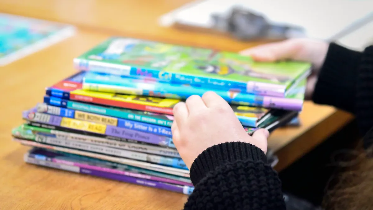 Image of a librarian's hands as she sorts through a pile of children's books that are out of focus.