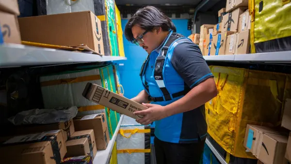 A delivery driver holds a package while wearing Amazon's smart glasses.