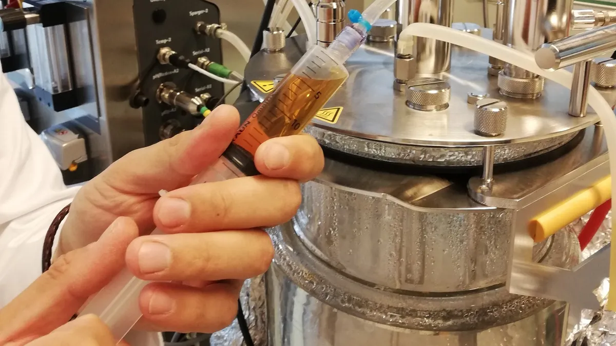 A pair of hands works with fermentation equipment in Paleo's lab.