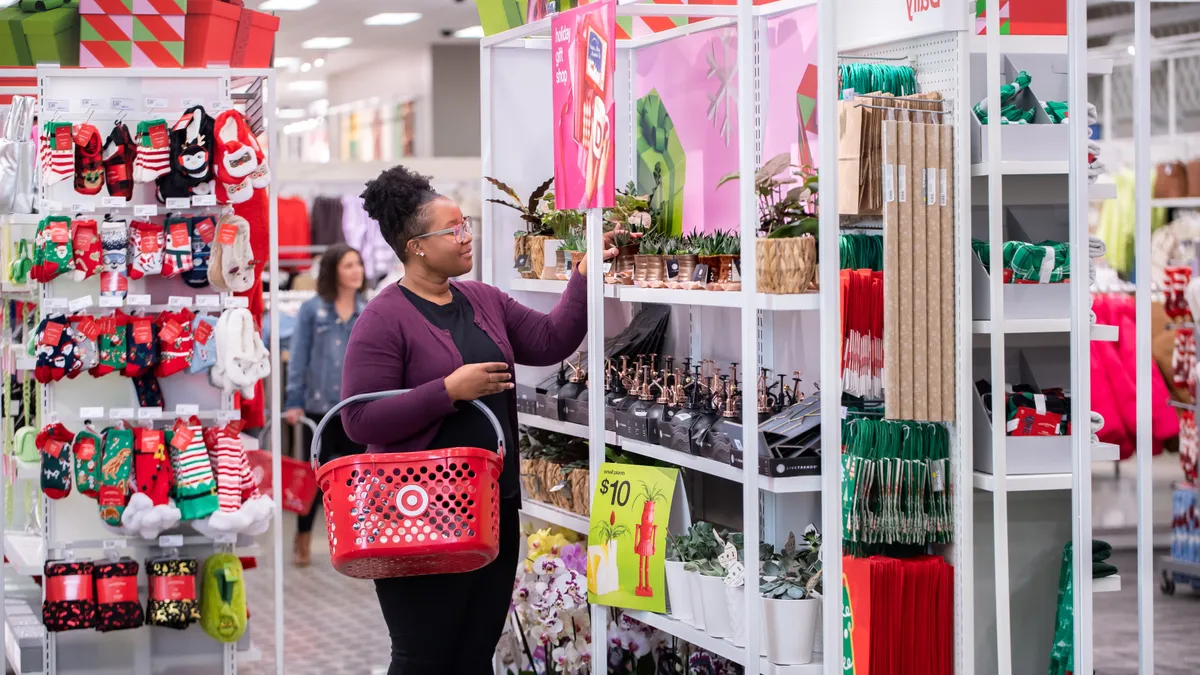 A shopper with a handheld basket broweses a display of holiday items at Target.