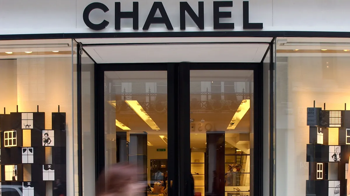 A person walks by a lighted Chanel storefront in the evening