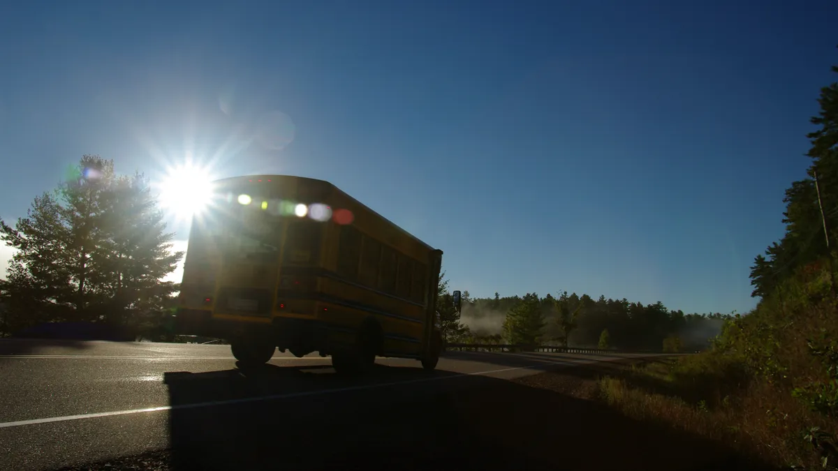 A school bus drives along a remote road in the early morning.