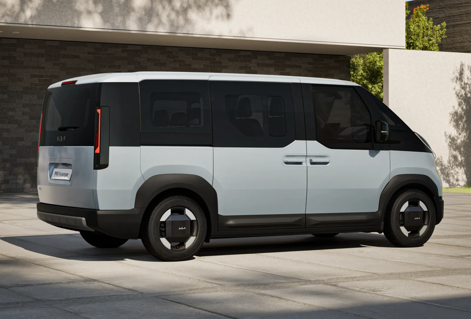 The Kia PV5 parked outdoor on a concrete surface with a building in the background.