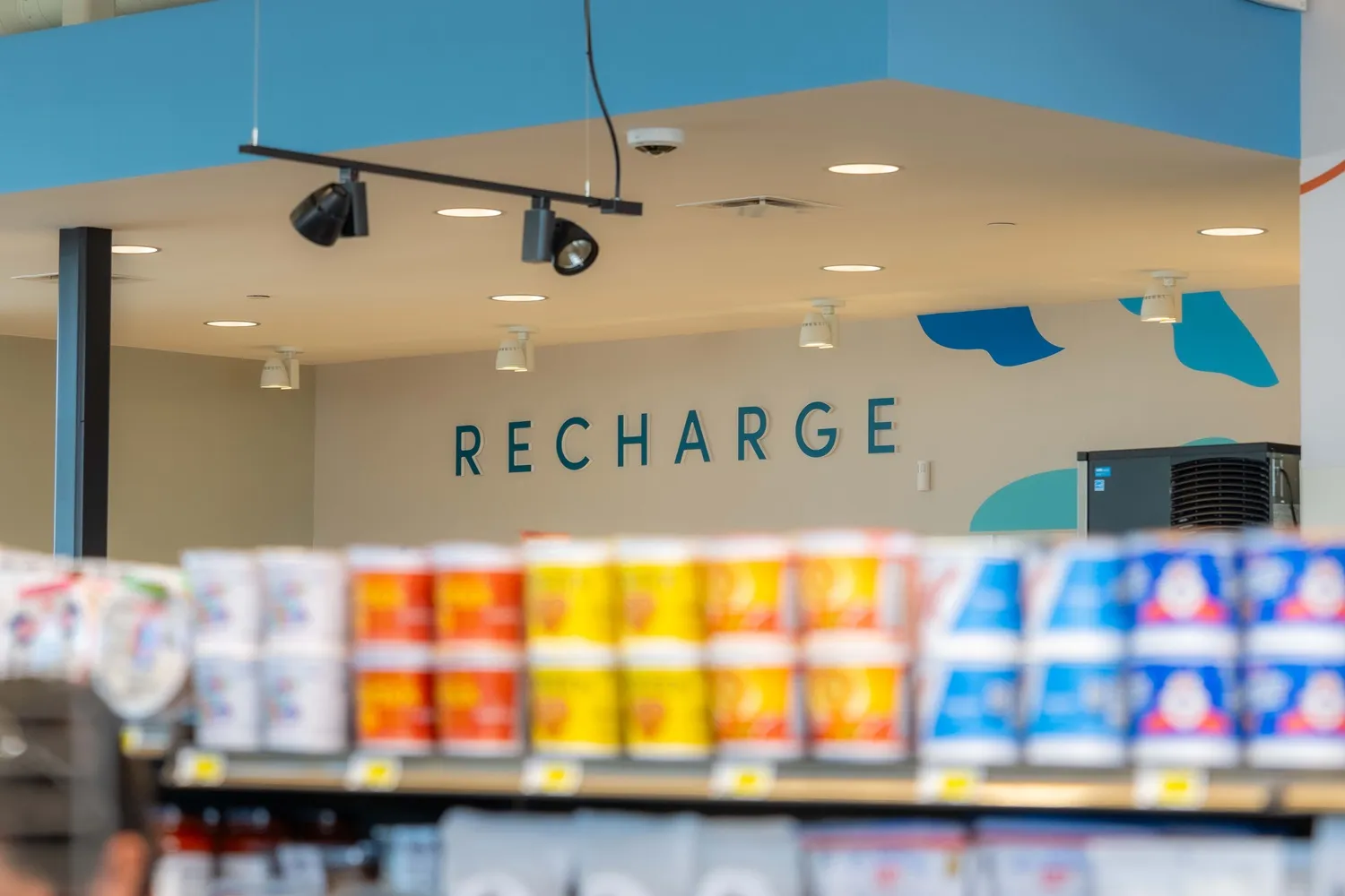 A photo of the interior of a convenience store. A sign on the wall reads &quot;Recharge.&quot;