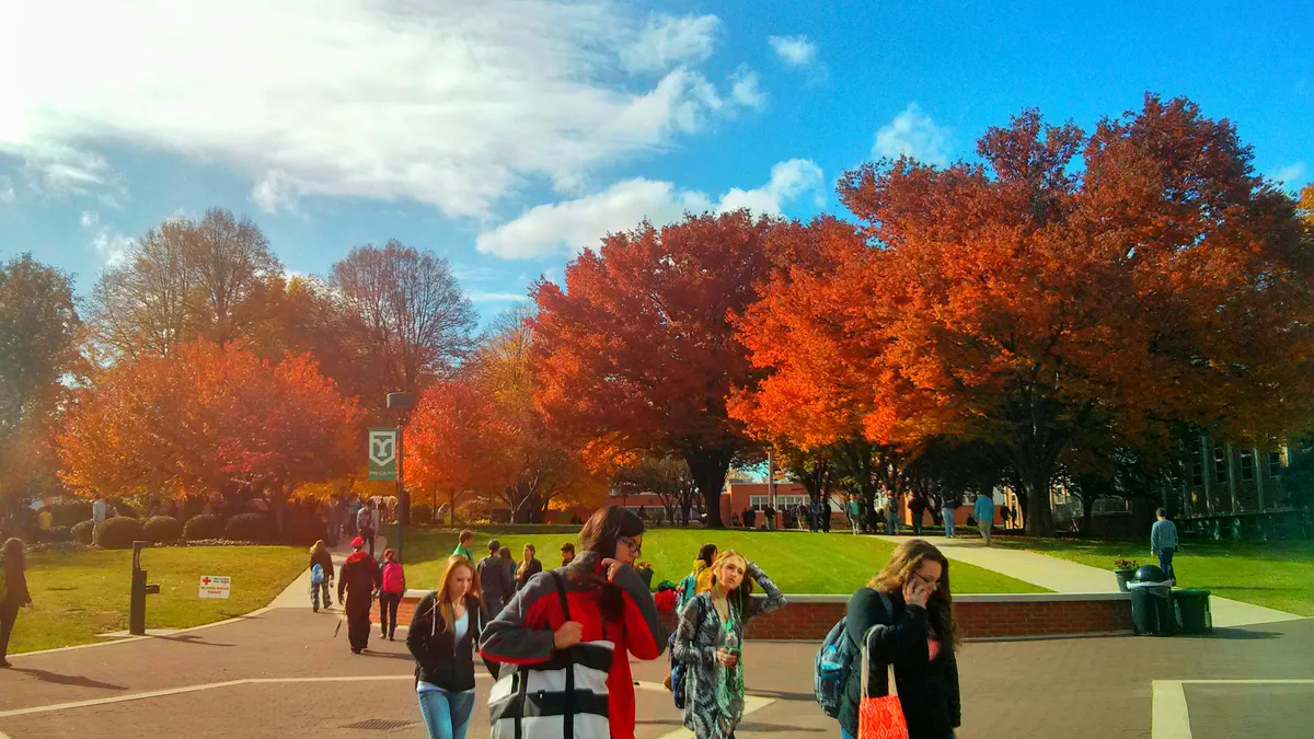 People walk across a brick path.