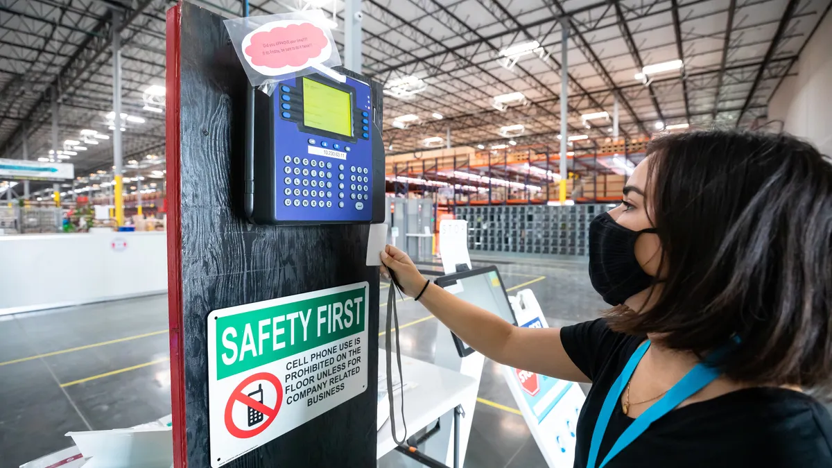 A young woman wearing a face mask clocks in at a fulfillment center.