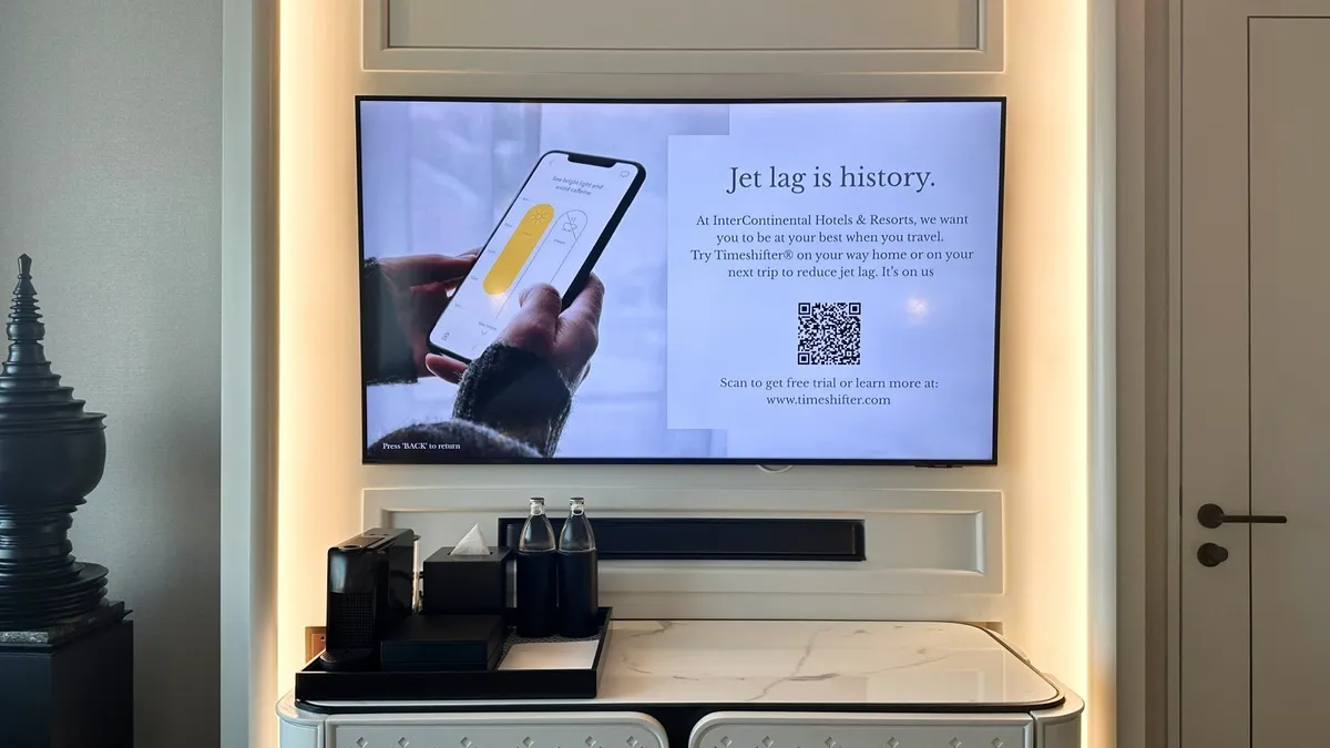 A TV screen displays a QR code for guests to scan that leads to the Timeshifter app.