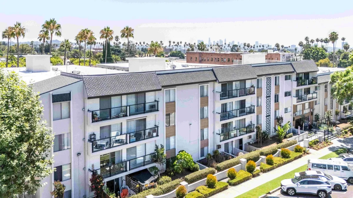 Aerial picture of three-story tan apartment project.