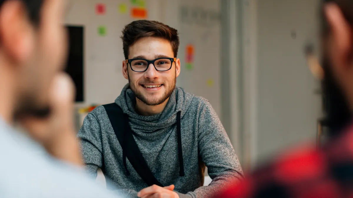 Young man at a job interview talking with two developers. They