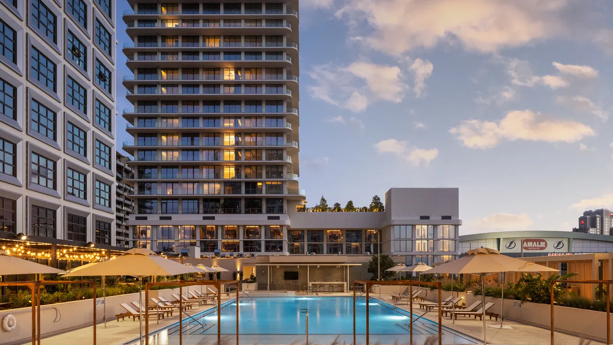 A pool area in front of an apartment tower.