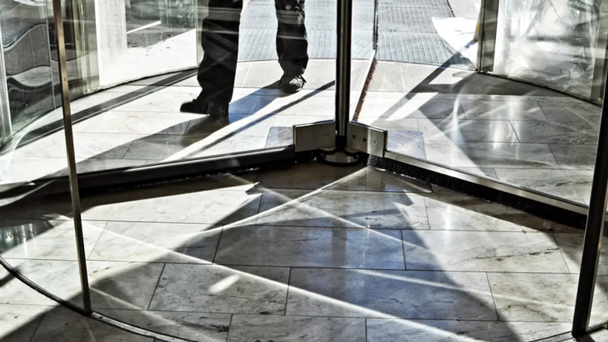 Close up of feet walking through a revolving door.