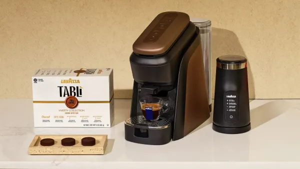 A Lavazza Tabli machine sits on a counter next to Tabli tablets.