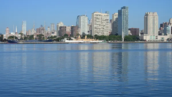 Tall buildings along a coast with large body of water in foreground.