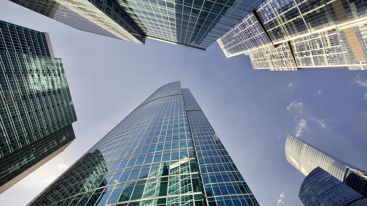 Office skyscrapers against bright sun and clear blue sky.