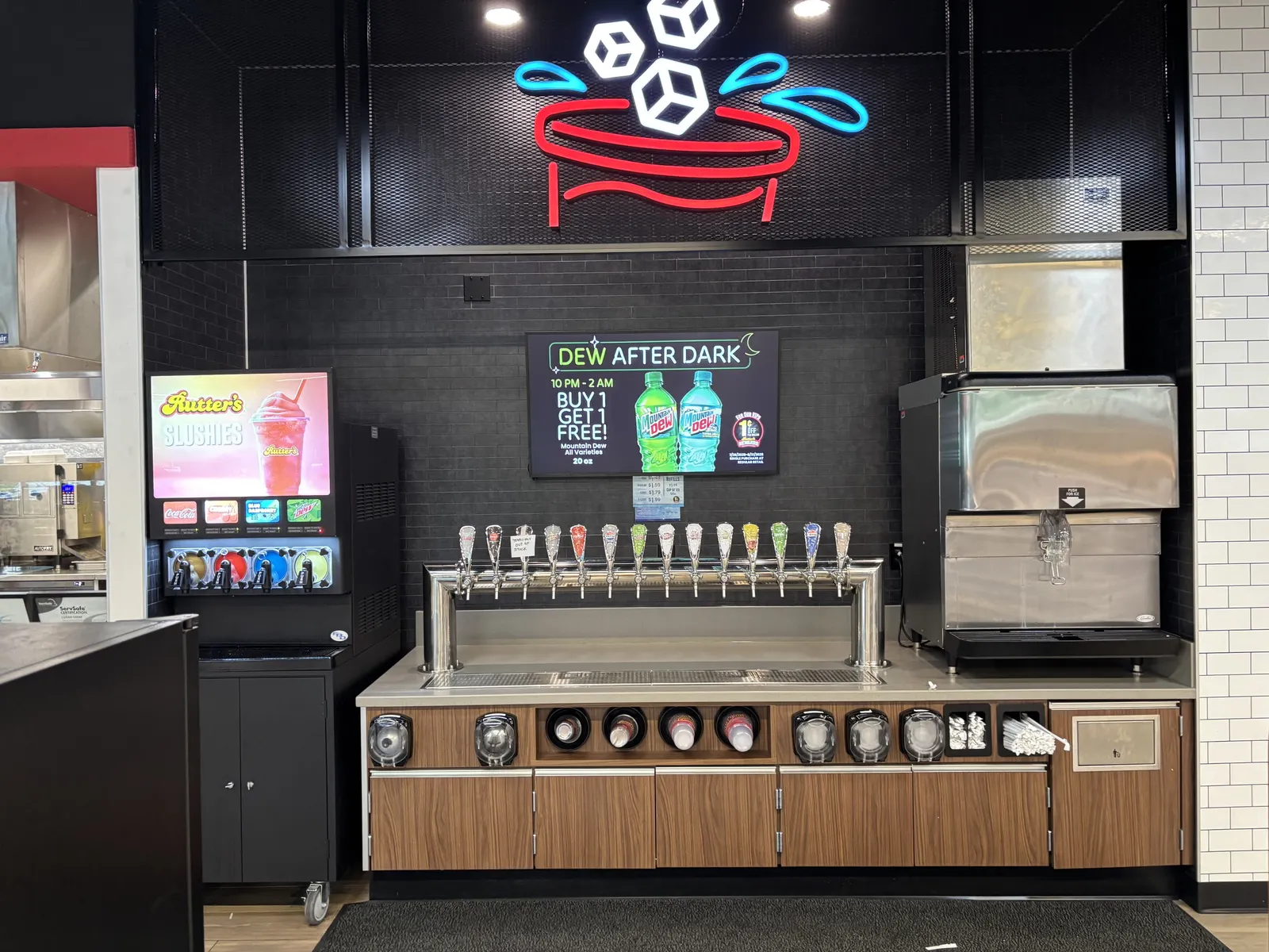A photo of a beverage area in a store. A sign behind the drink taps says &quot;Dew after dark.&quot;