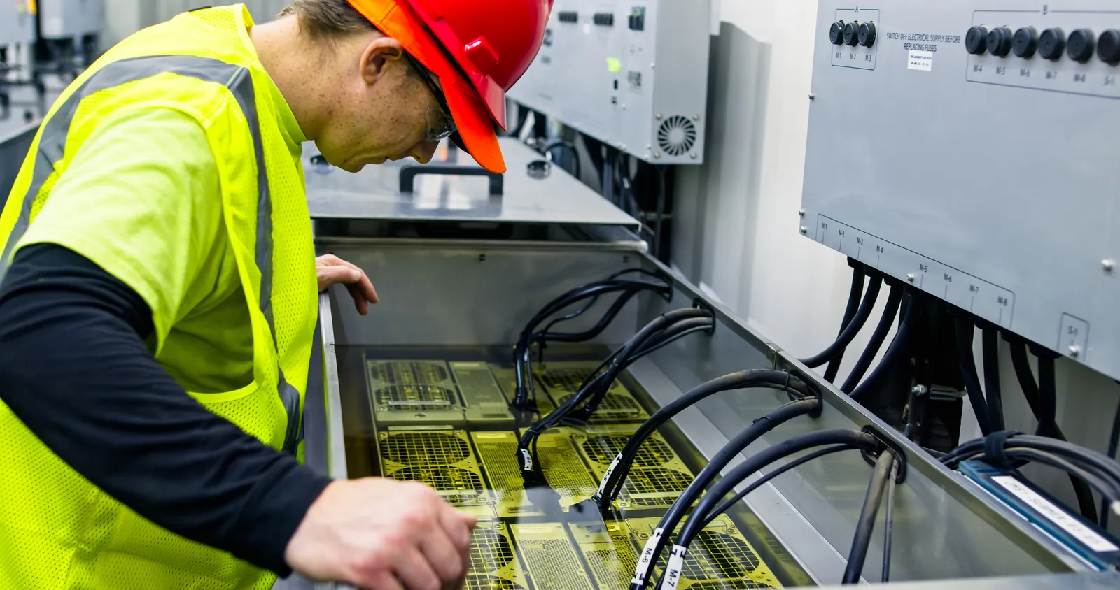 A technician inspecting a data center server in an immersion cooling tank.