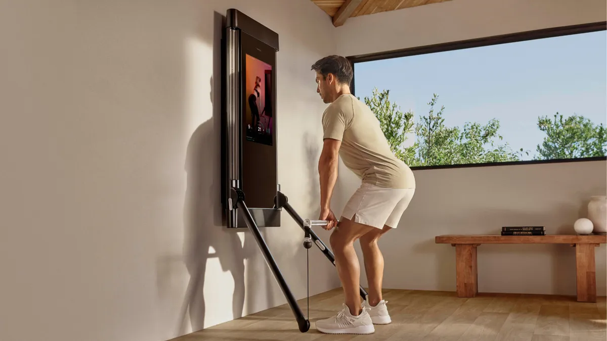 Person uses mounted fitness mirror equipment from Tonal