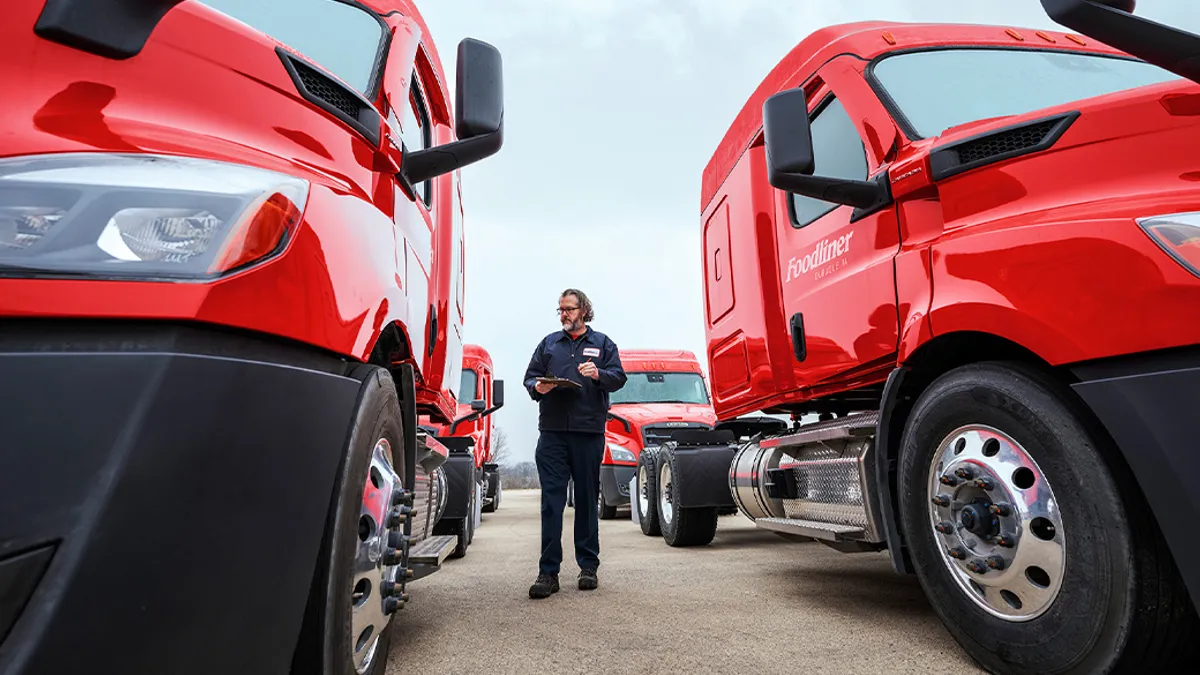 Worker standing between 2 parked commerical trucks.