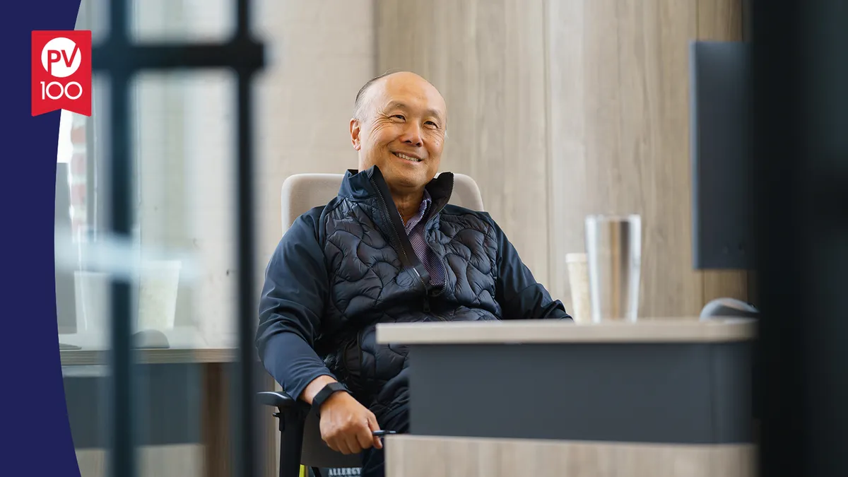 A portrait of Frank Lee framed with a banner icon that reads "PV 100"