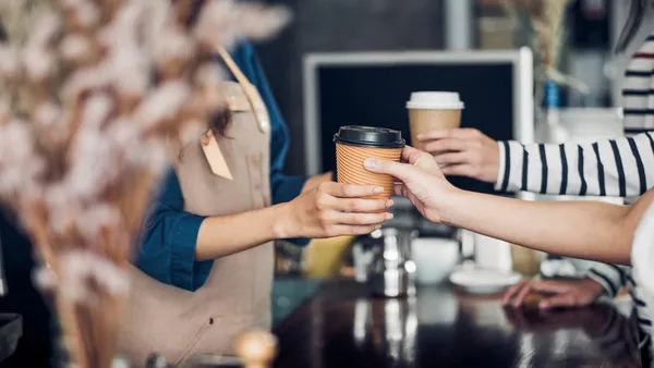 A barista hands off coffee at a cafe.