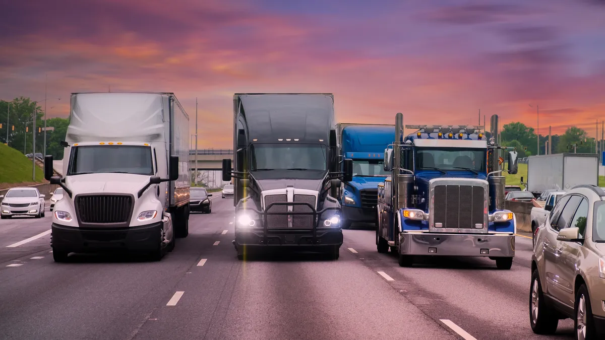 A row of trucks in different highway lanes face the direction of a camera amid traffic in Atlanta.