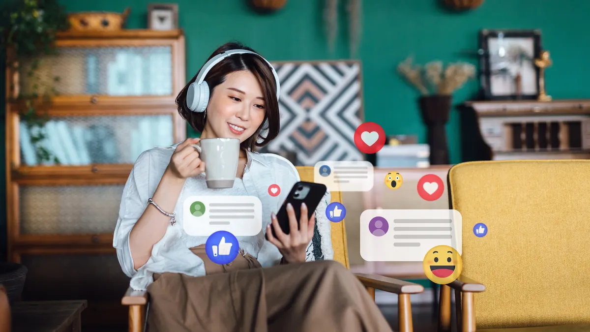 Woman with headphones relaxing at home and using smartphone