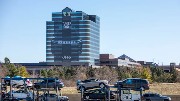 An office building depicts the image of a car and the words "There's only Wagoneer S" on one external side, while a car hauler truck passes by in the foreground.