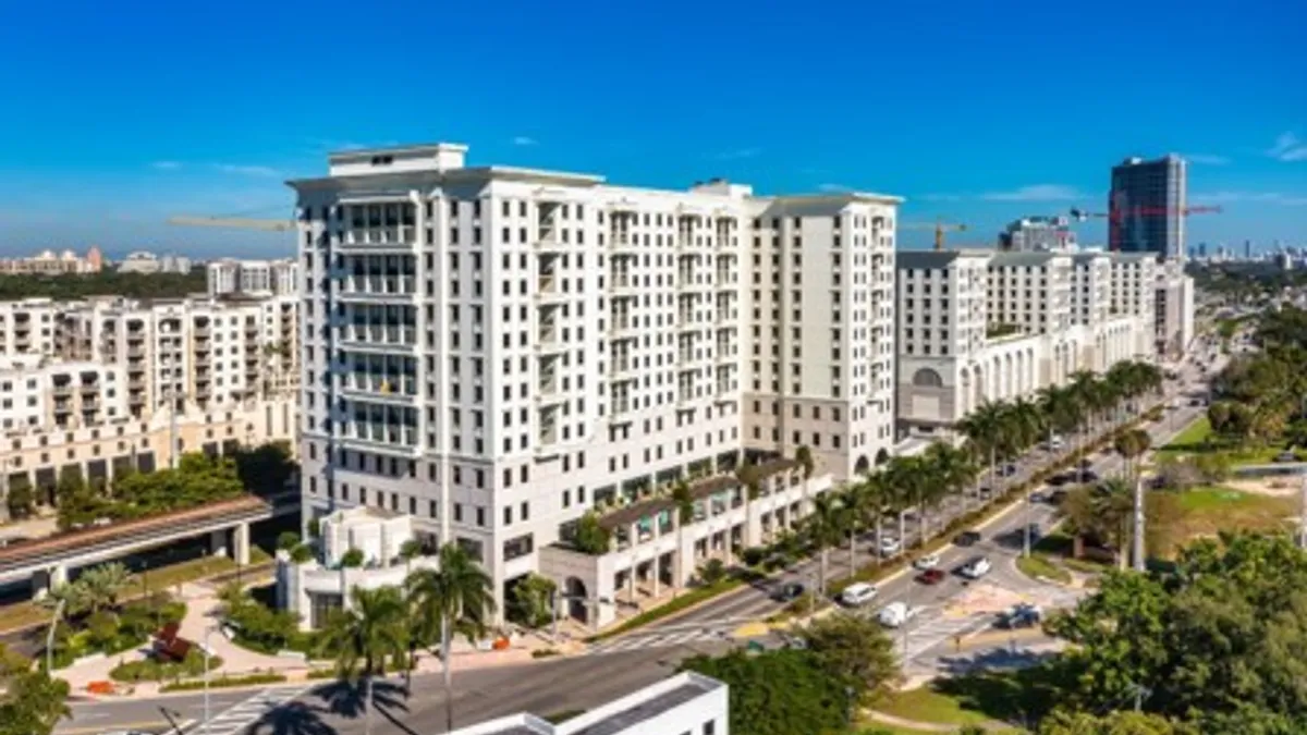 Aerial shot of white, high-rise apartment building.