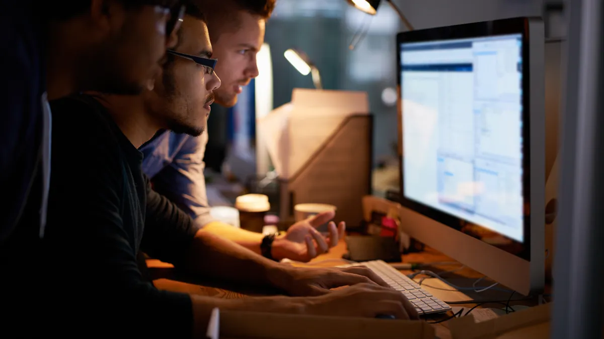 A group of co-workers surround a computer screen