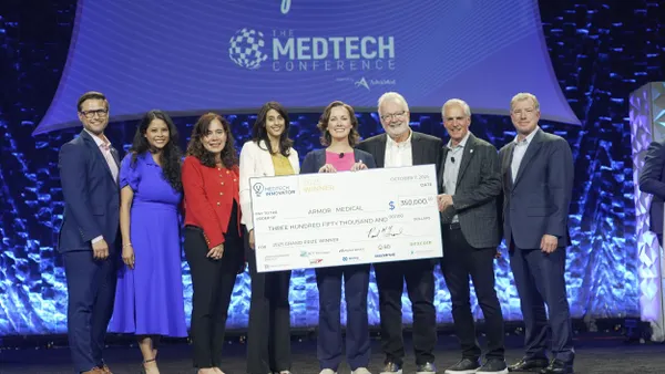 Eight people line up behind a giant check.