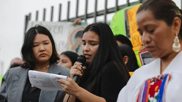 Three people speaking at a protest.