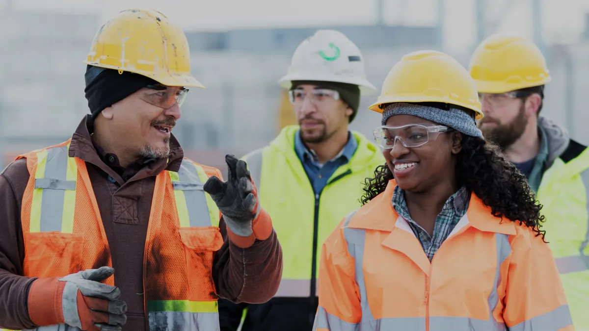 A group of people in safety gear walking and talking on a construction jobsite.