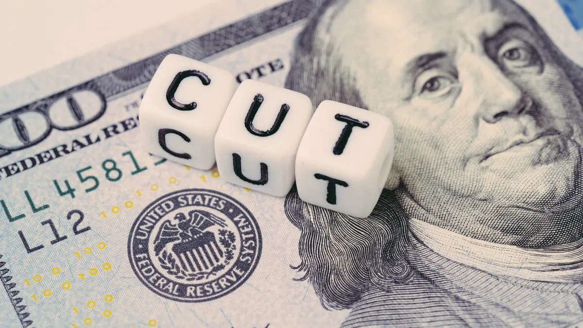 Three dice spelling out the word "cut" resting on $100 bill